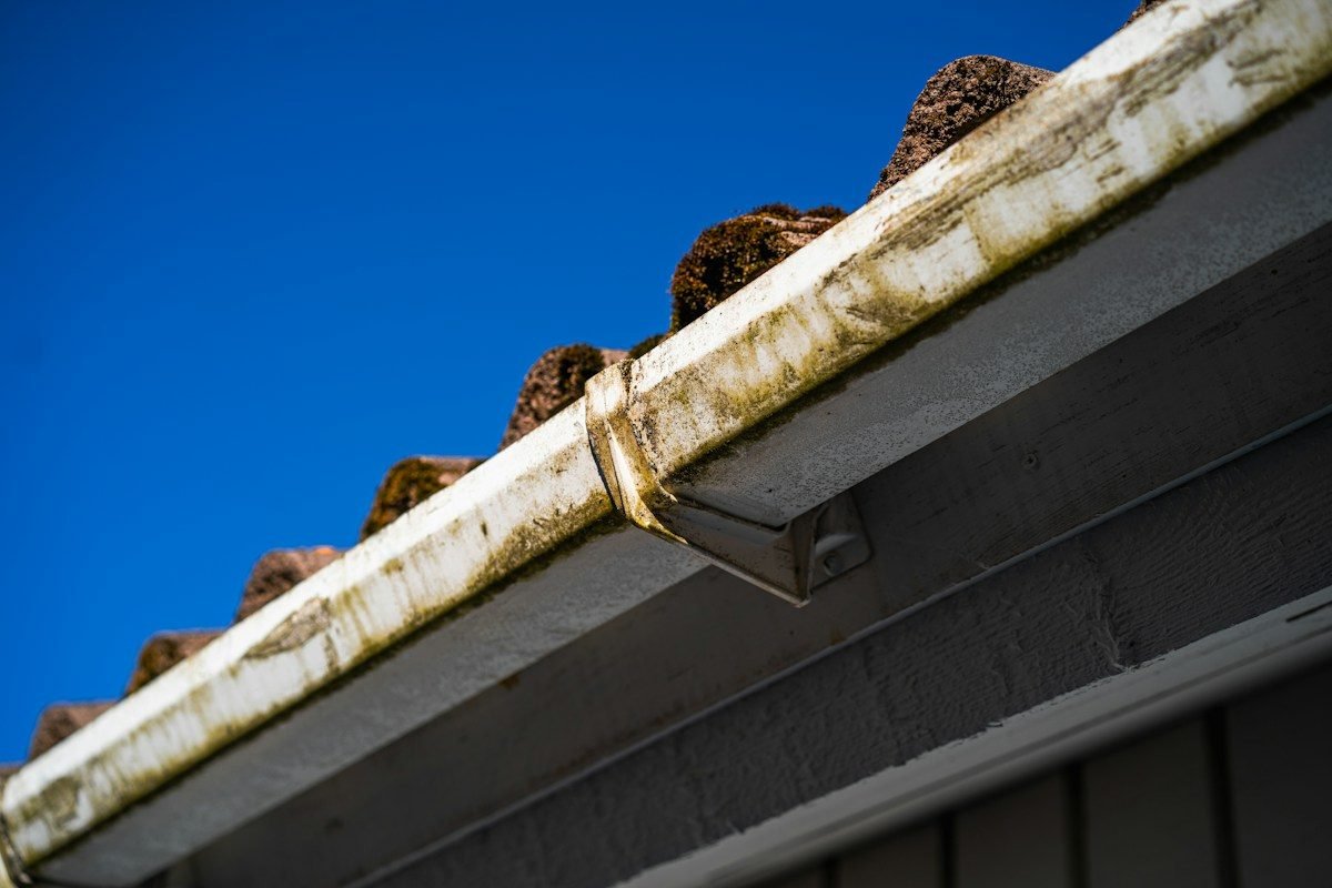 A roof edge and gutter seen from below against a blue sky